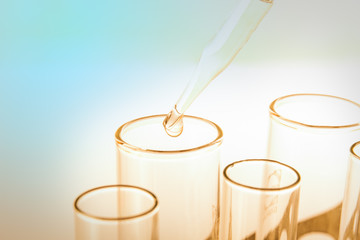 Laboratory pipette with drop of liquid over glass test tubes