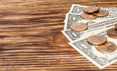 One dollar banknotes and one dollar coins on wooden background