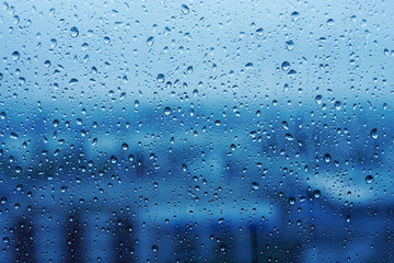 Water Drops on Glass with Blurred Cityscape View in Rainy Season