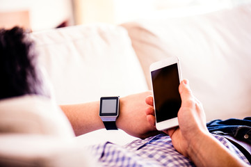 Unrecognizable man at home using smartphone and smart watch