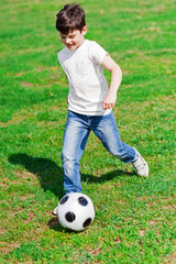 Obraz premium Pretty male child playing football on grass