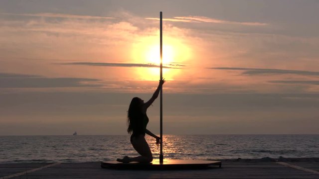  Strong young woman doing pole dancing fitness exercise on the beach in summer evening against the setting sun professional poledancer performing pole tricks outdoors part_S6 FS7 10-bit 4:2:2