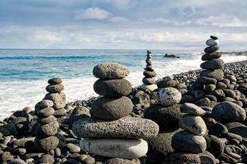 Stack of zen stones over water and blue sky. 