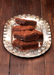 Pieces of chocolate cake brownies on a silver plate, vertical
