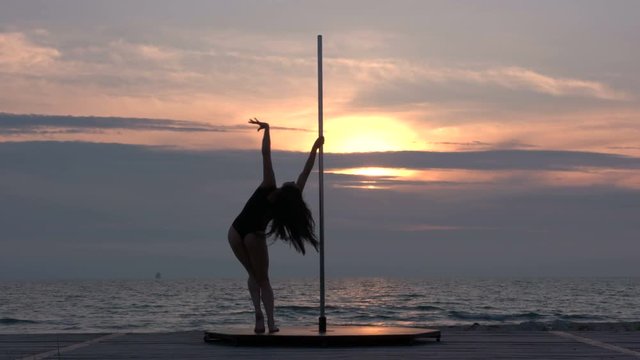Fit girl poledancer performs fitness pole dance on the portable dancing stage at sunset silhouette of flexible young woman against the setting sun in summer evening part_sun4