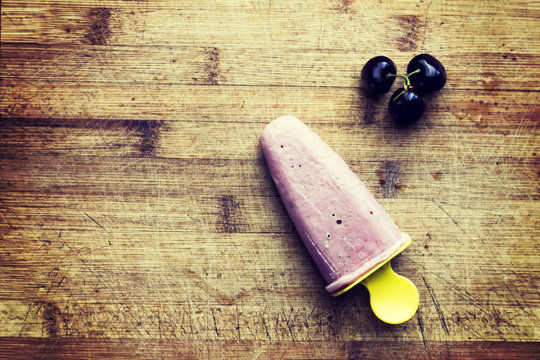 Homemade cherry popsicle with berries on wooden background. Flat lay. Top view. Toned picture