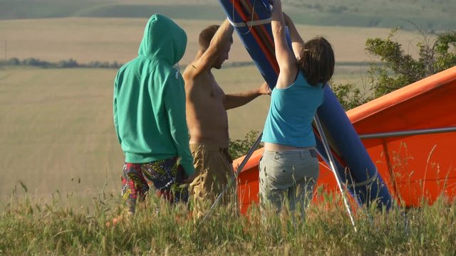 Group of young people prepare the hangglider for flight