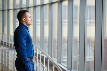 Businessman standing near the window and looking into it