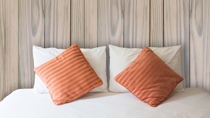 white pillow and orange pillow on bed.