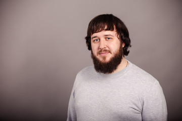 Unleashing his emotions. Side view of furious young bearded man shouting while standing against grey background