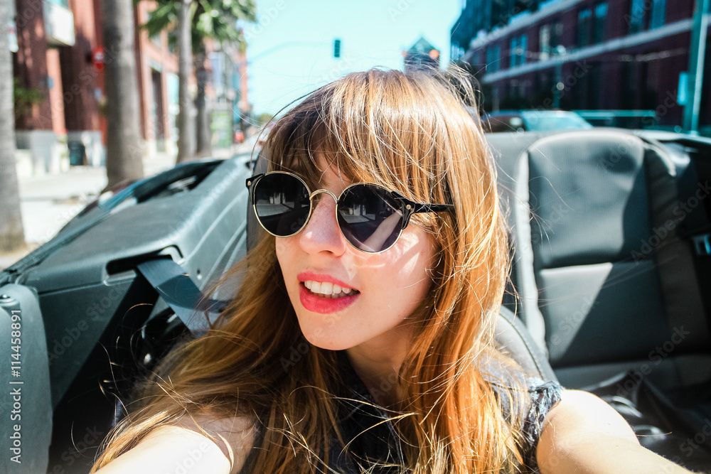 Poster young girl in a convertible at san francisco, california