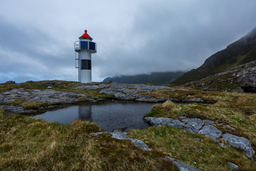Small lighthouse on a rock with puddle on the foreground, Norway