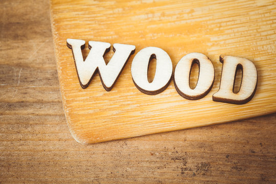The word wood in wooden letters on wooden background. Toned photo.