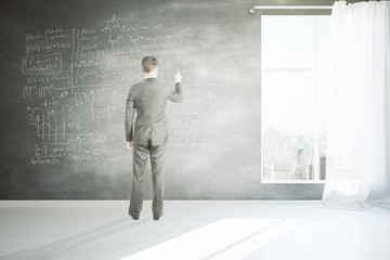 Fototapeta premium Man writing formulas on wall