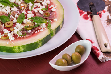 Cut watermelon pizza with crumbled feta cheese and prosciutto and basil.