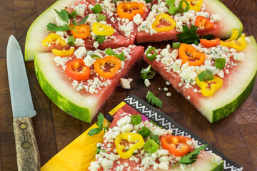 Cut vegetarian watermelon pizza with crumbled blue cheese, bell peppers and parsley.