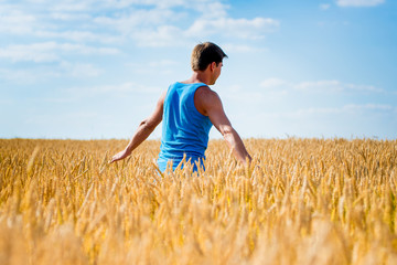 Young happy man in a wheat field.
