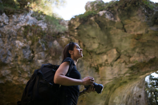 Woman traveler photographing and exploring a cave.Travel and adventure concept.Woman Caver Spelunker exploring inside of a cave.Woman holding her camera in a cave