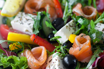 Salmon salad with brie and olives closeup. Smoked salmon, brie, olives, lettuce and pepper mix with herbs. Mediterranean tasty snack background