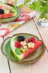 Piece of fruit watermelon pizza with fresh berries, banana, kiwi