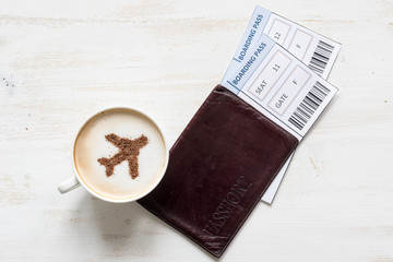 Aircraft symbol made of cinnamon in cup of cuppuccino, boarding passes and passports. Traveling concept