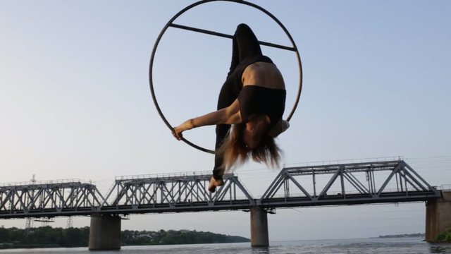 Beautiful woman doing acrobatic elements hanging on a bridge