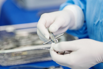 Close-up of scrub nurse taking medical instruments for operation