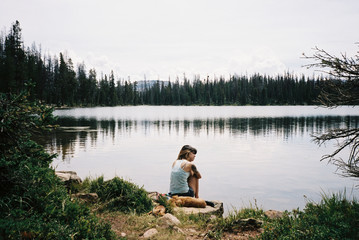 Woman sitting by lake, High Uintas Wilderness area, Utah, America, USA