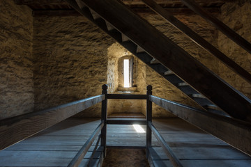 Dark room with stone walls window and wooden staircase