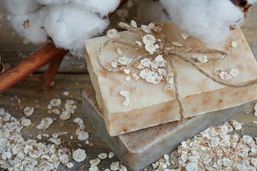 Natural handmade soap, oat flakes and cotton branch on wooden ba