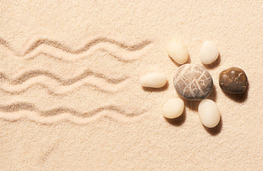 Fototapeta na wymiar Turtle made of sea stones on sand. Summer beach background