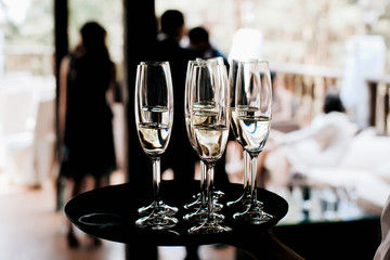 waiter brings full glasses of champagne on a tray