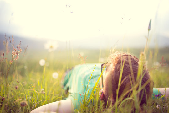 Carefree happy man lying on green grass meadow in mountains enjoying the sun on his face.Enjoying nature sunset.Freedom.Enjoyment.Relaxing in mountains at sunrise.Sunshine.Daydreaming
