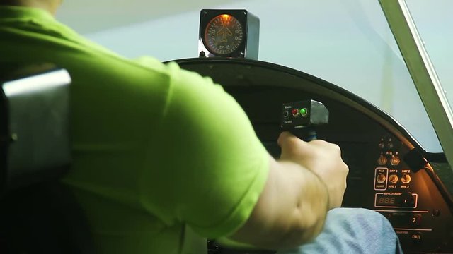 Male teenager sitting in airplane cockpit simulator and showing OK hand sign