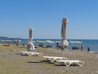 Белые зонтики и лежаки на пляже, качели у моря, курорт...