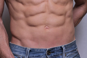 Strong Athletic Man showing muscular body and sixpack abs over white background close up