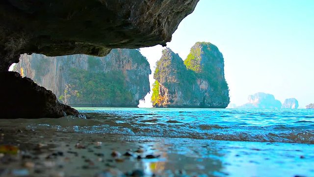 Video FullHD (1920x1080) - Gentle waves at low tide, gradually undercutting and eroding massive rocks and cliffs along a tropical coastline at low tide, with sound.