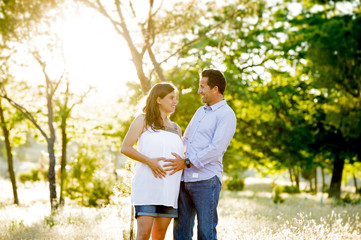 young happy couple in love together on park landscape sunset with woman pregnant belly