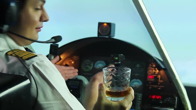 Funny pilot sitting in plane cockpit and refusing glass of whiskey, lifestyle
