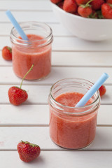 Erdbeersmoothies mit Strohhalmen in Marmeladengläsern