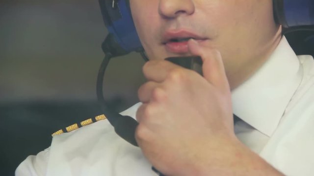 Thoughtful pilot talking to dispatcher over radio set and navigating plane