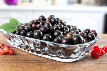 Plate of red currant on the wooden board. Top wiew, closeup. White kitchen at the background