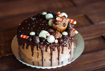 homemade cake decorated with sweets, cupcakes and waffles.