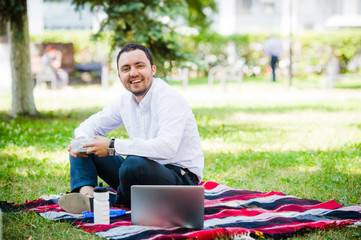 Young and attractive man relaxes in the park at lunch time
