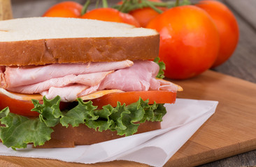 Ham Sandwich Closeup With Tomatoes in Background