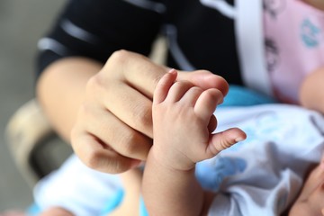 Photo of newborn baby feet and hand in soft focus