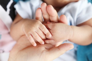 Photo of newborn baby feet and hand in soft focus