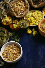 Assortment of dry medicinal herbs in bowls on wooden background top view