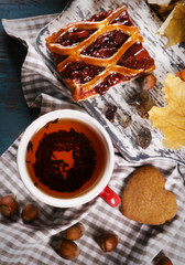 Cup of tea with autumn decor on wooden table.