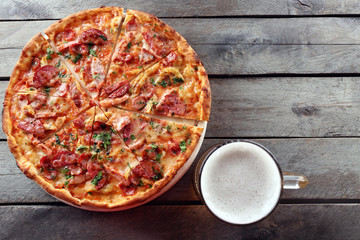 Tasty pizza and glass of beer are on wooden table, close up